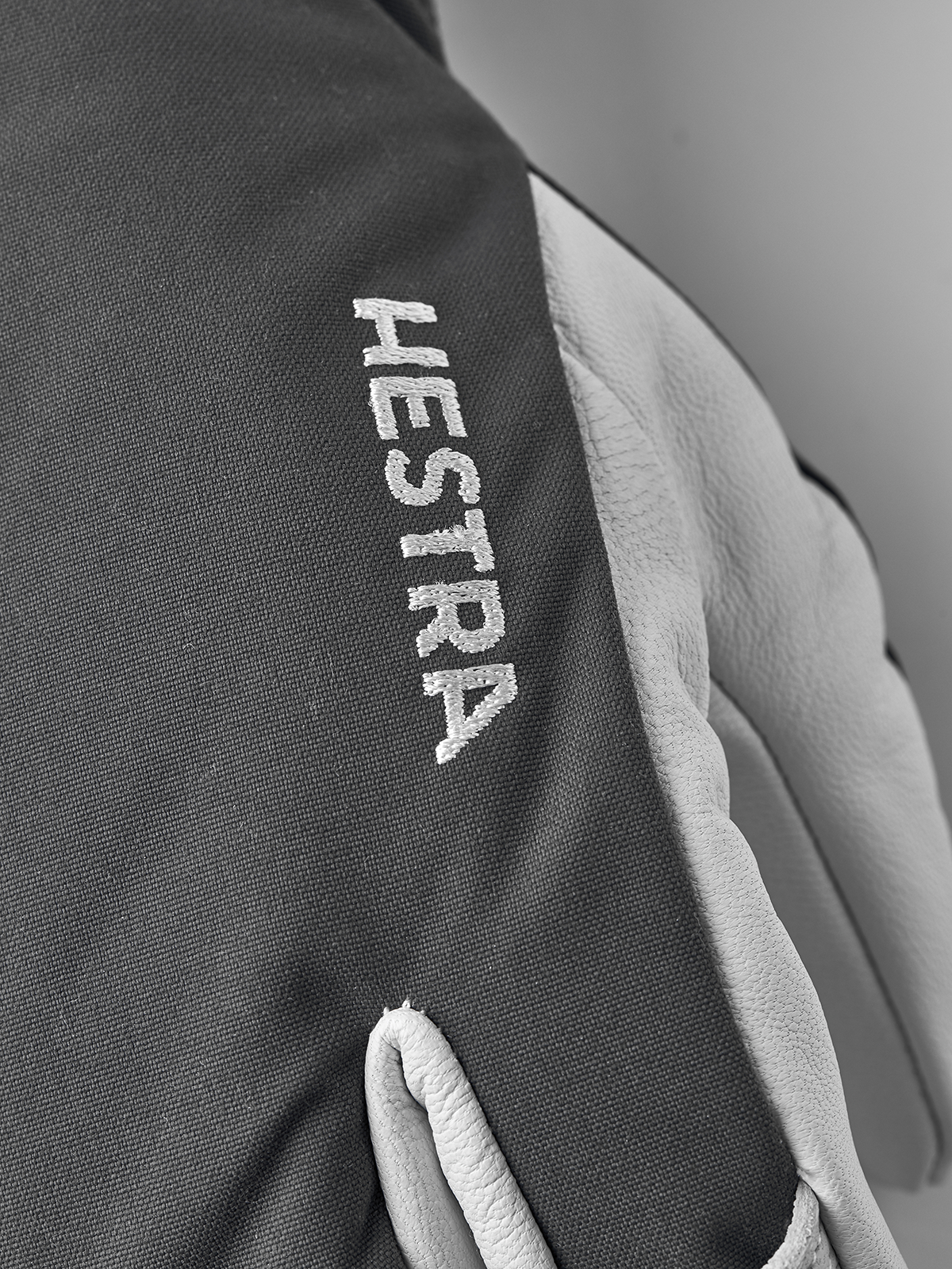 Dark grey 3-finger ski glove with white Hestra text and light leather palm