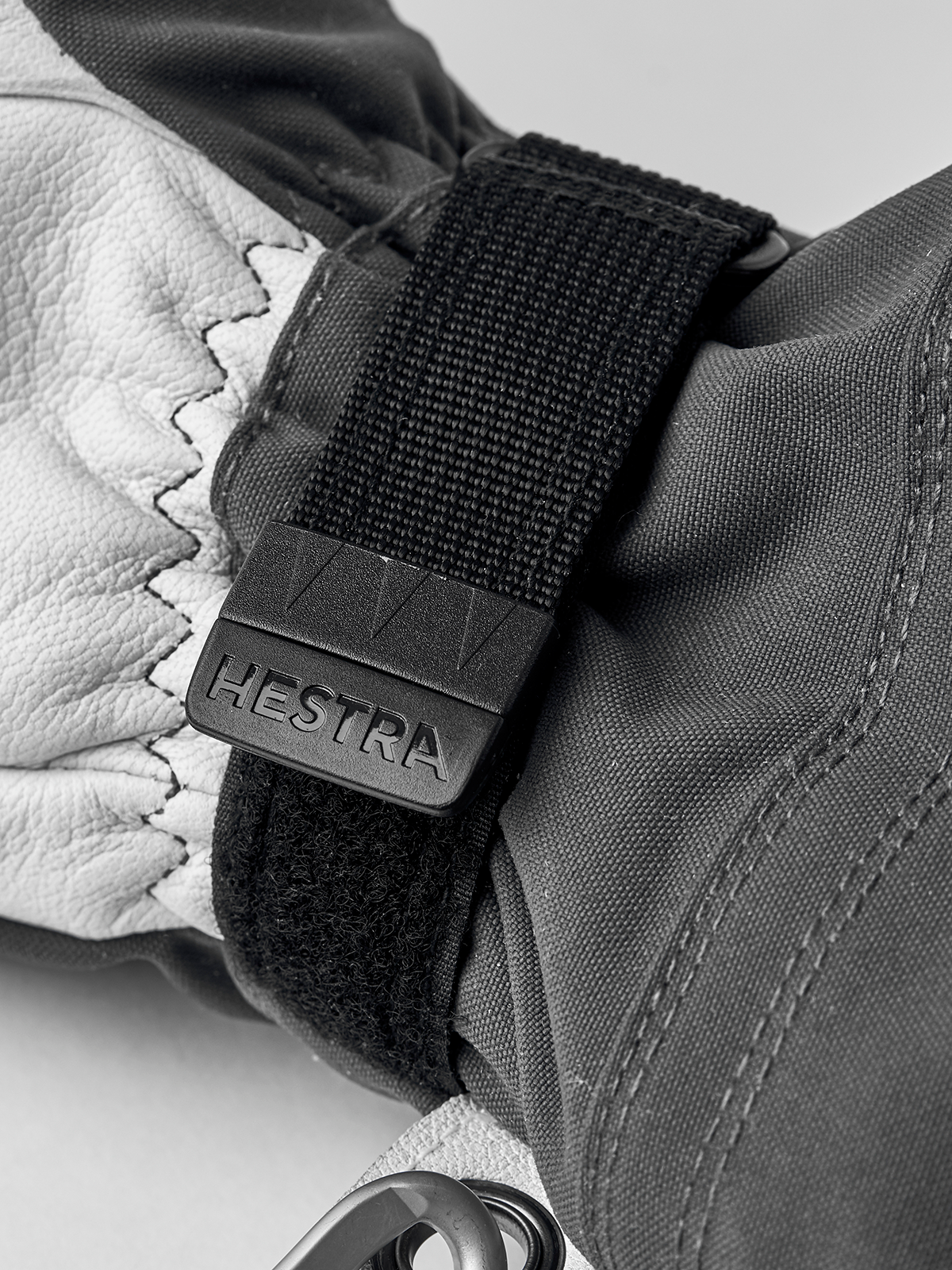 Black and white Hestra ski glove with hook-and-loop wrist strap and logo patch