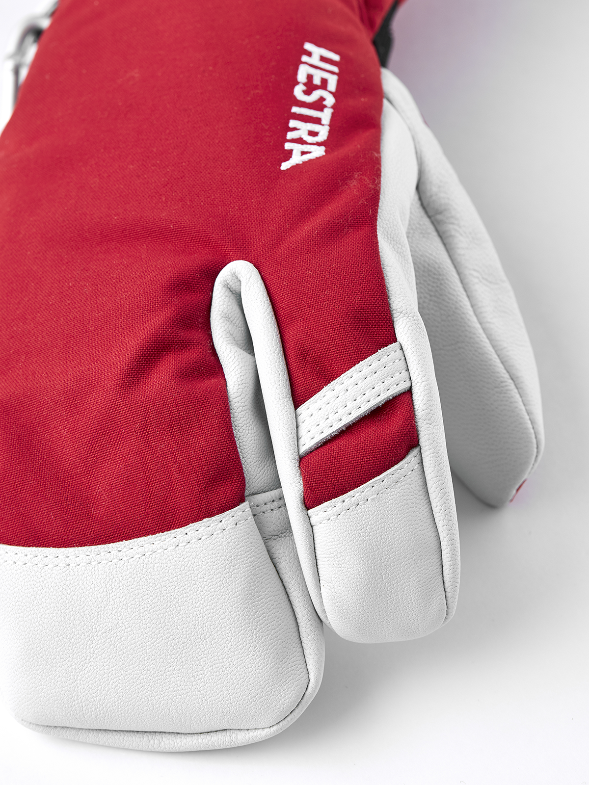 Red and white 3-finger ski gloves with Hestra print on the back of the hand