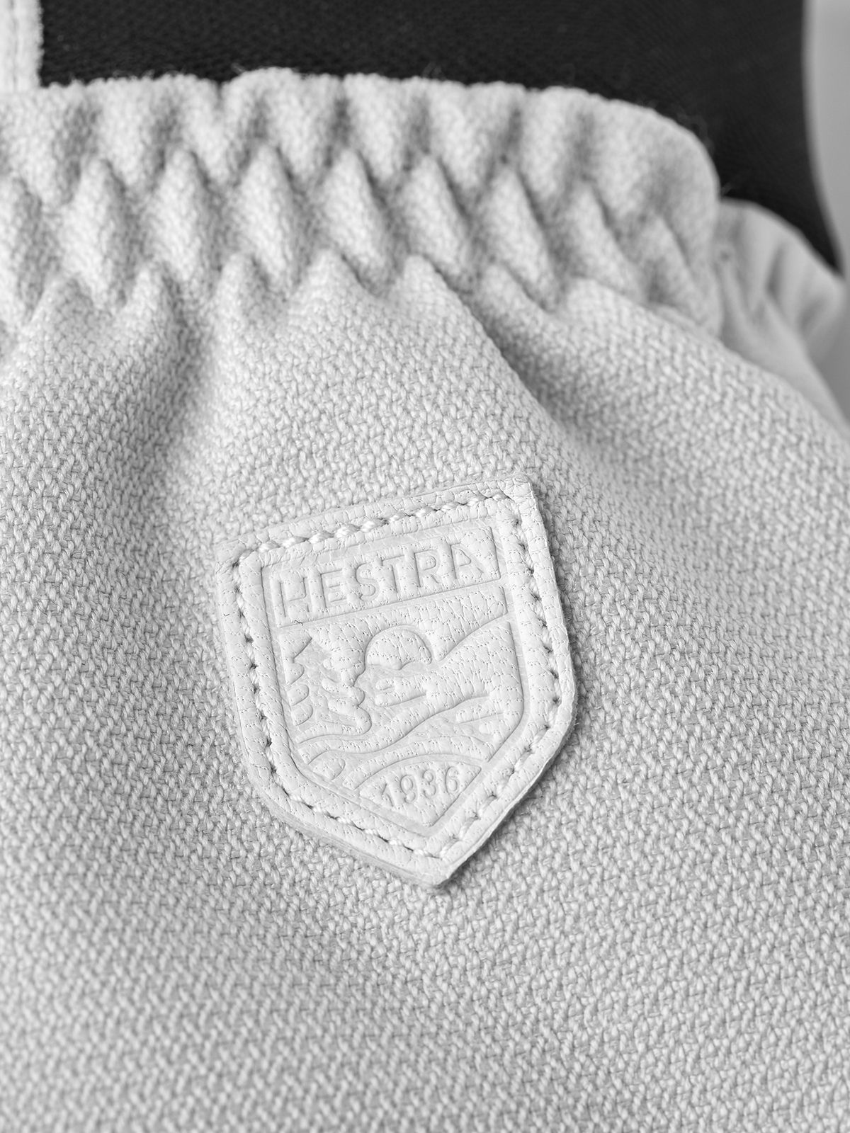 Light-colored patrol glove with textured knit cuff and Hestra shield logo patch