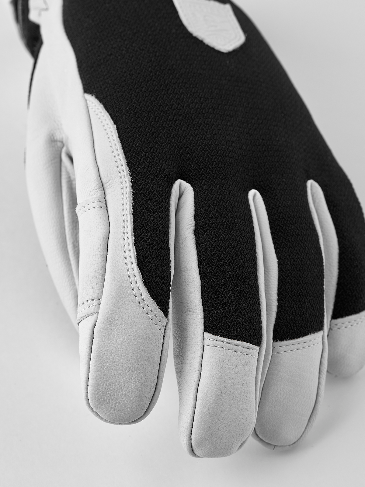 Black patrol gloves with white leather palm and side stitching, showing five finger sections.