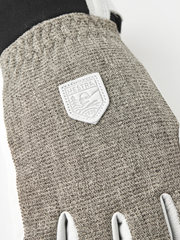 Close-up of textured gray fabric patrol glove with leather brand patch and white cuffs.