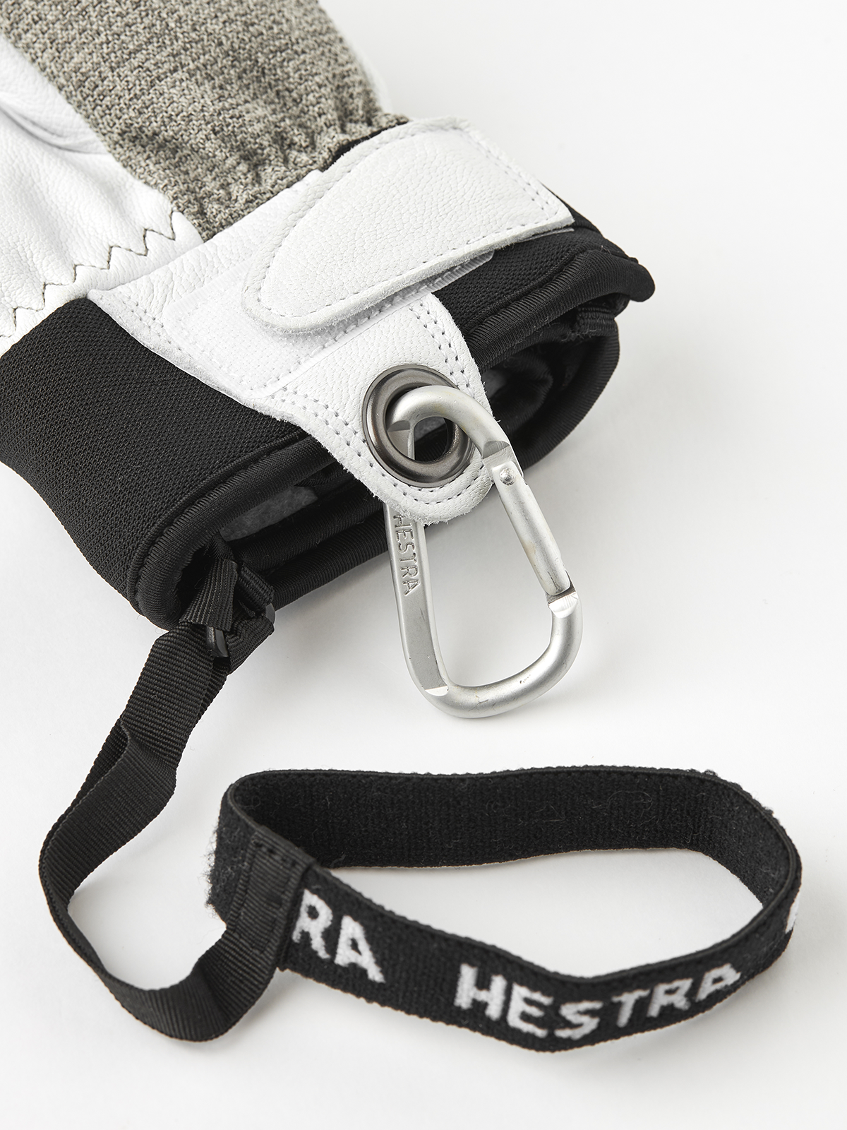 Leather glove cuff with carabiner clip and black wrist strap labeled Hestra