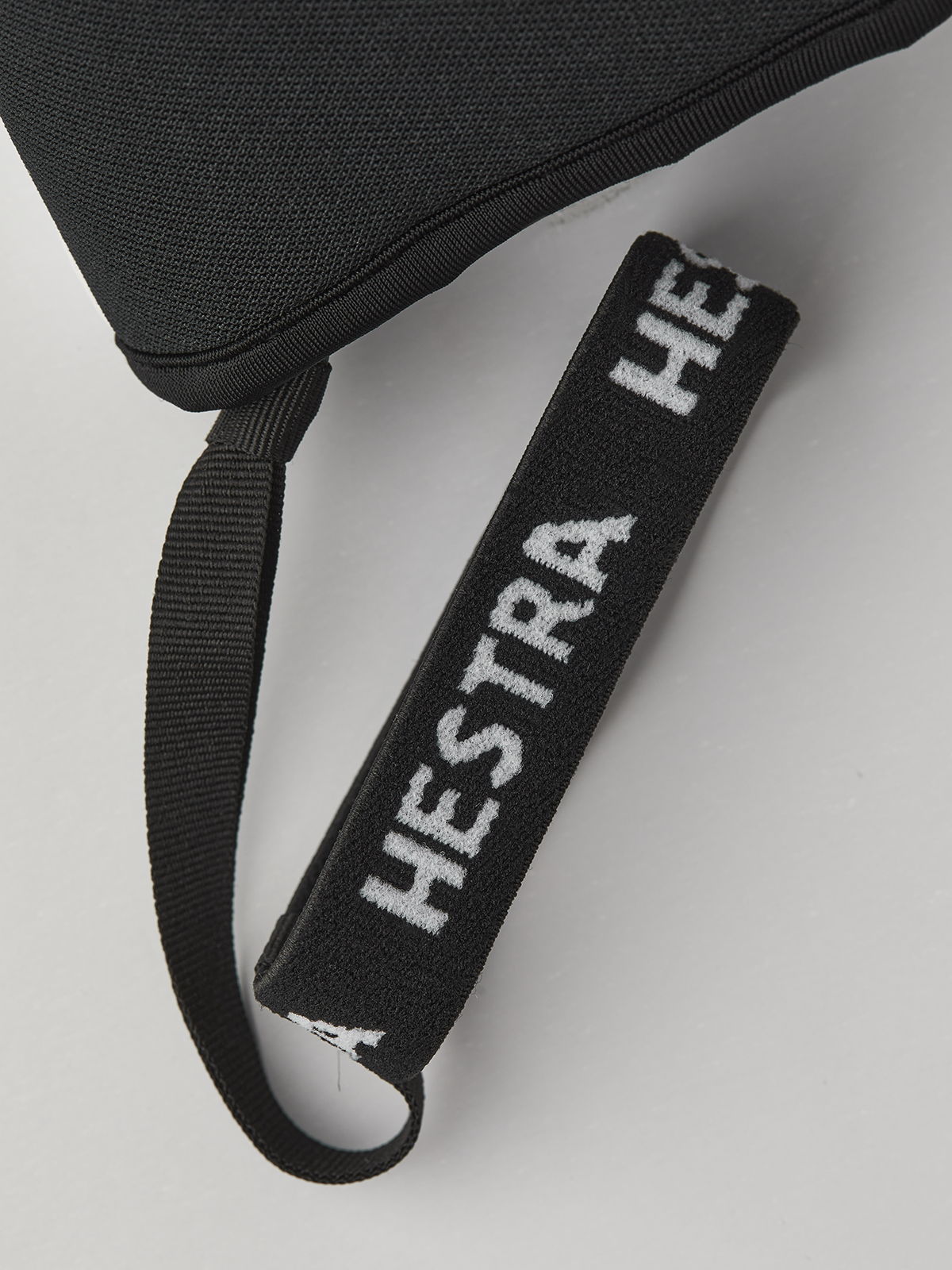 Black wrist strap with 'HESTRA' embroidered lettering on glove.