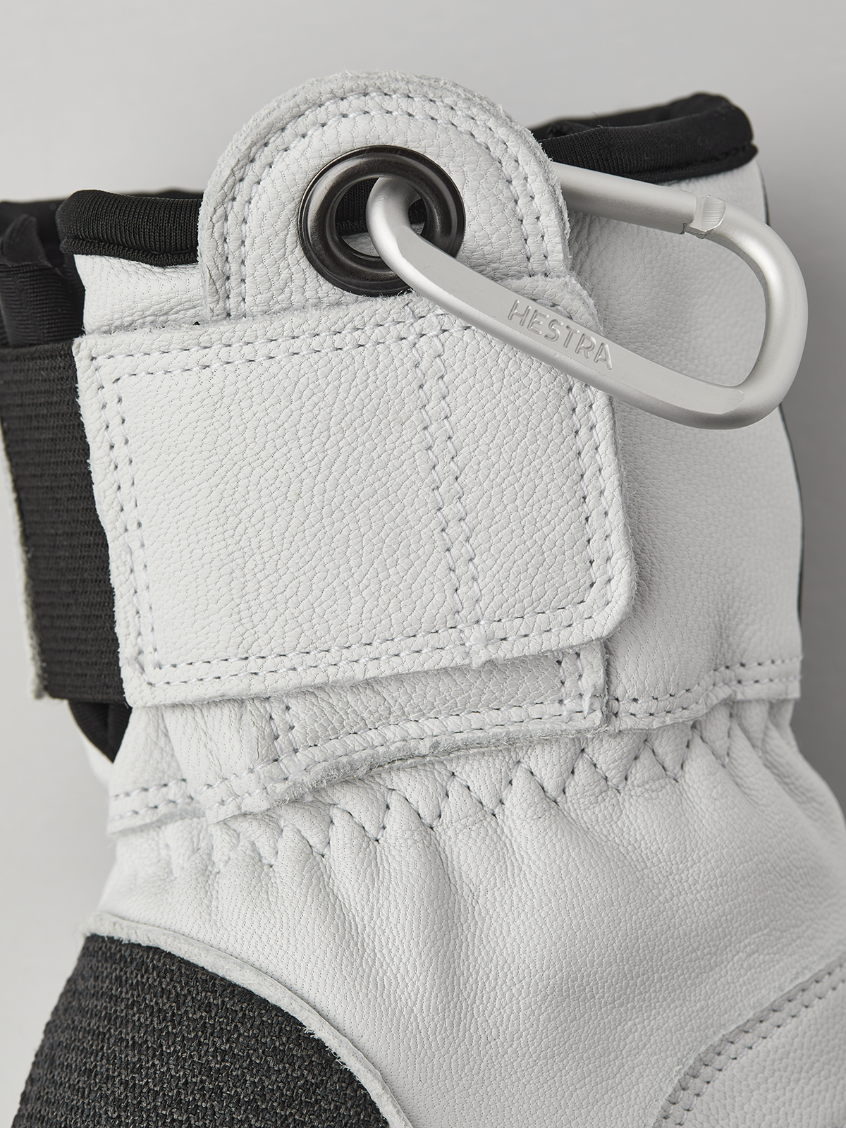 White 3-finger leather glove close-up with metal ring and reinforced wrist strap