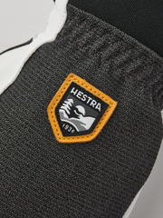 Dark gray knit glove with tan-trimmed Hestra brand patch.