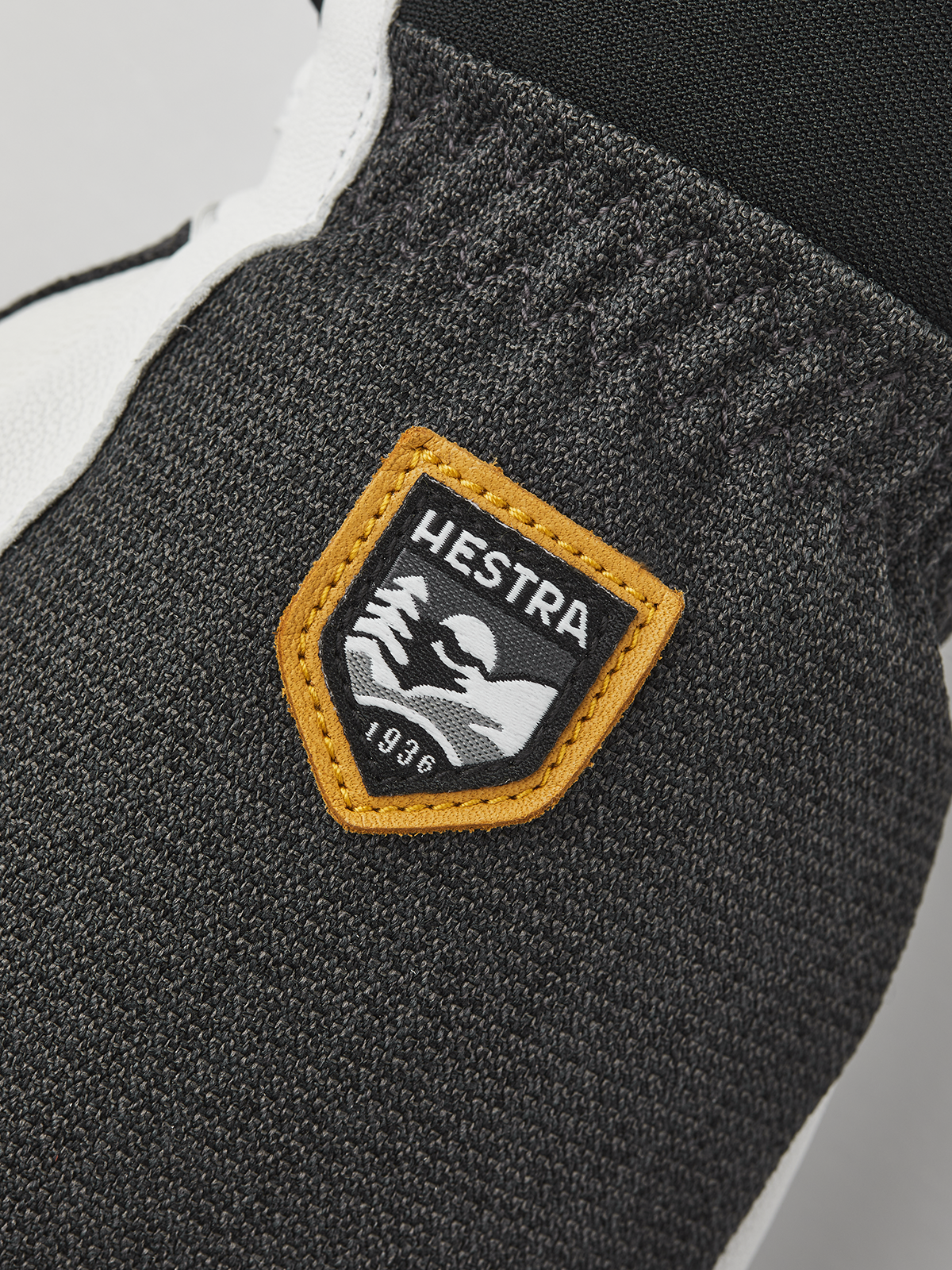 Dark gray knit glove with tan-trimmed Hestra brand patch.