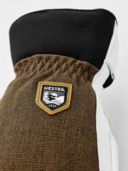 Olive-brown glove cuff with Hestra shield patch and white leather side.