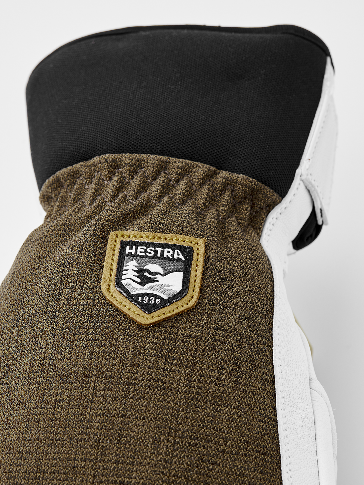 Olive-brown glove cuff with Hestra shield patch and white leather side.