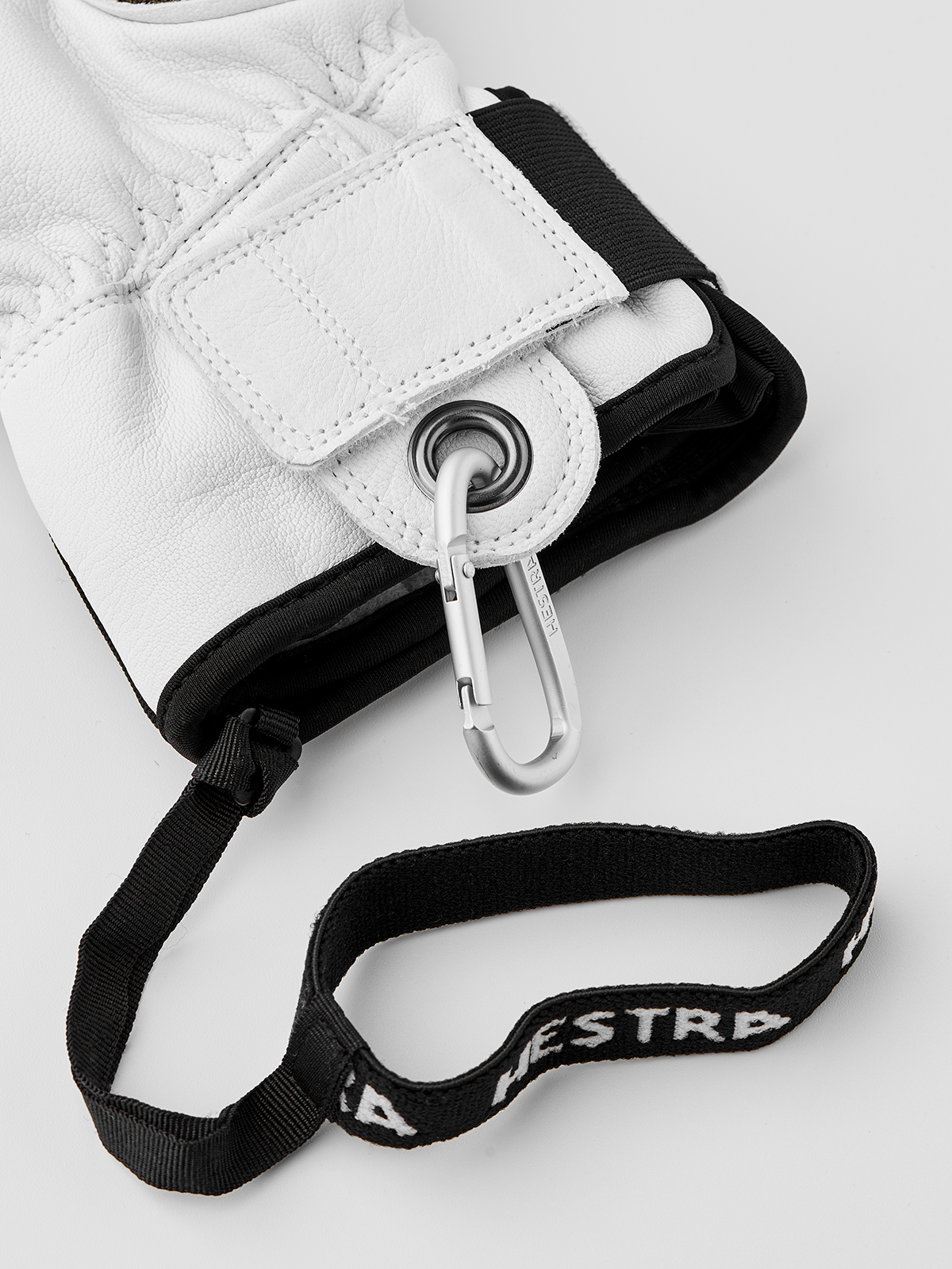 White leather patrol gloves with black strap and metal carabiner attachment.