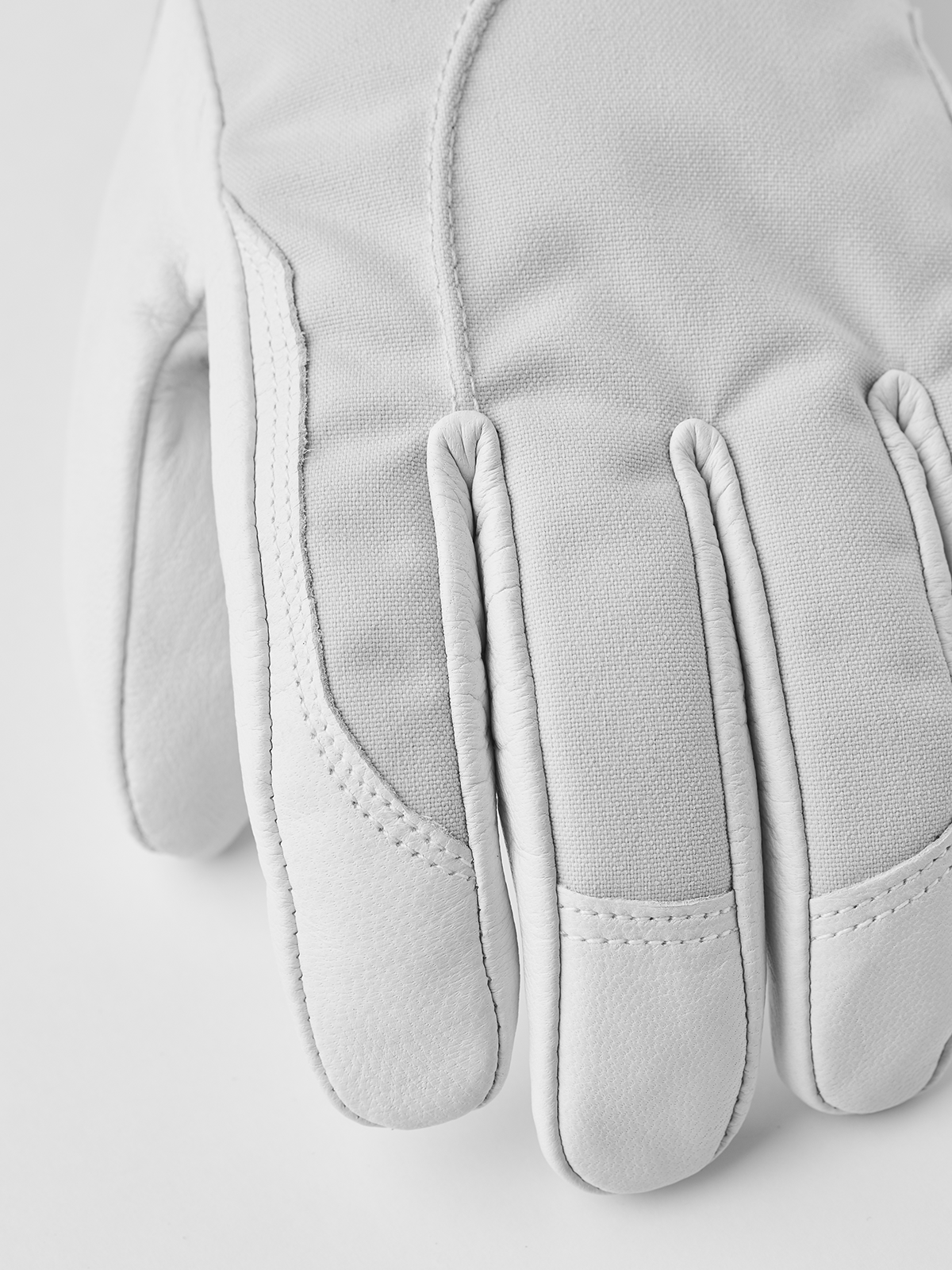 Pair of white ski gloves with stitched fingertips and padded palm
