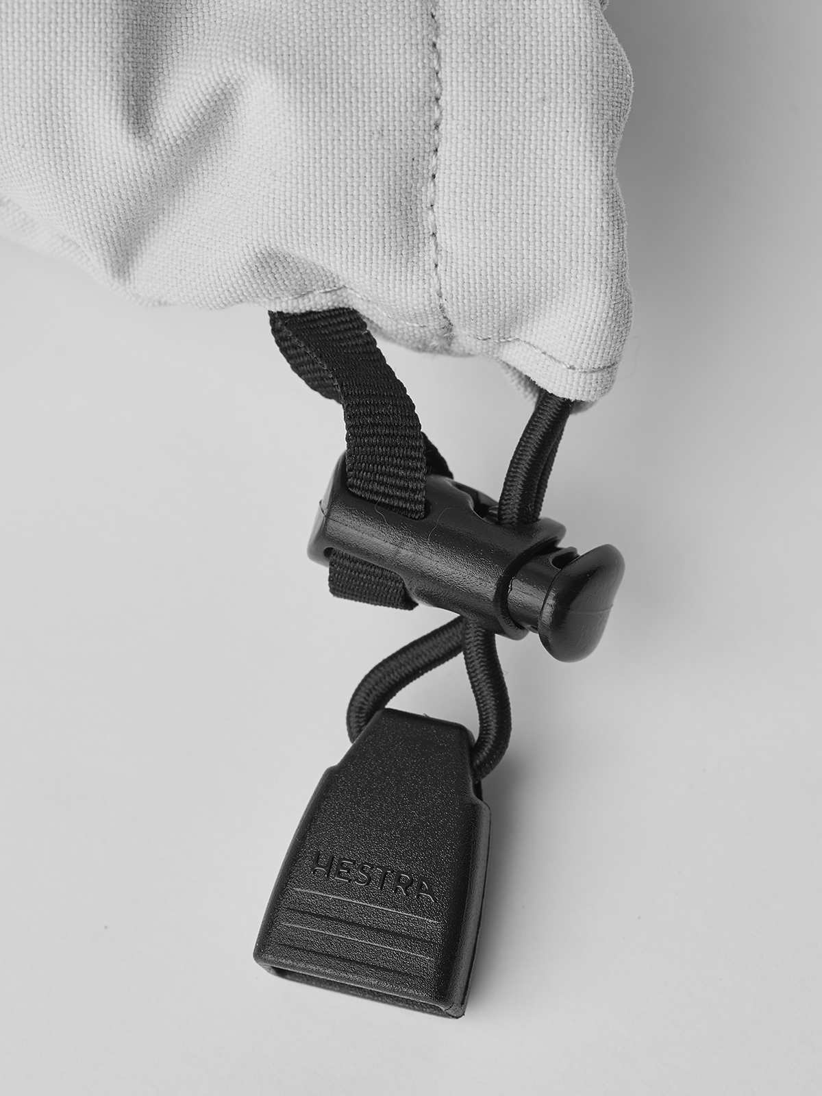White ski glove with black webbing strap and gray carabiner hook
