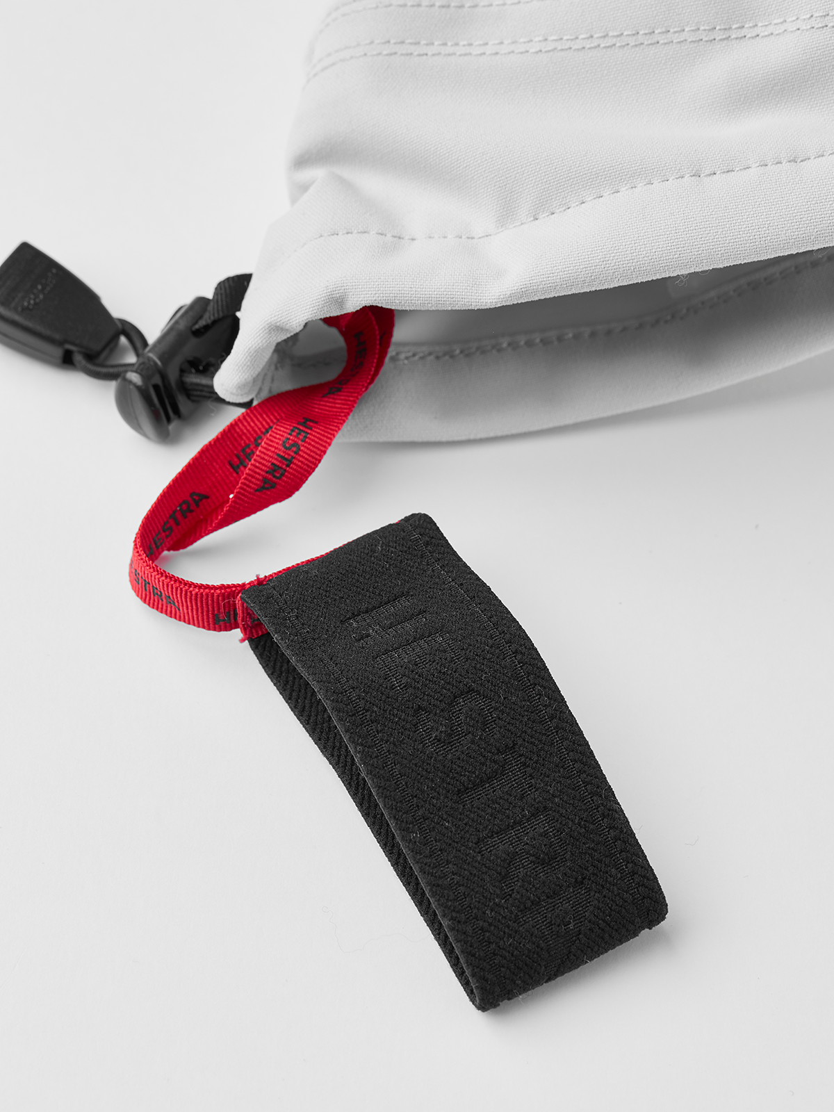 White ski glove with black cuff strap and red pull tab