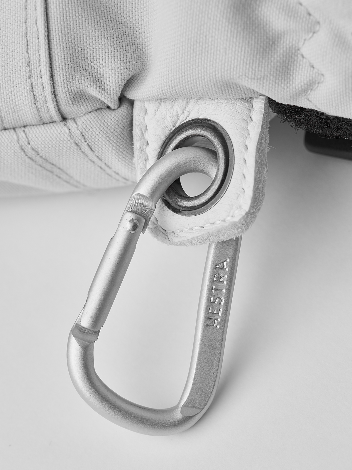 White ski glove with silver carabiner and round metal ring at wrist