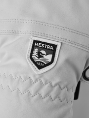 Off-white ski glove close-up with Hestra logo patch and quilted cuff detail