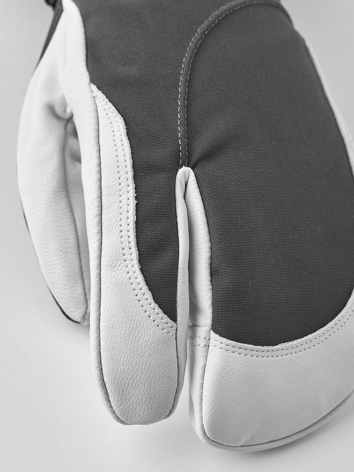 Dark-and-white ski glove with curved knuckle seam and textured palm panel