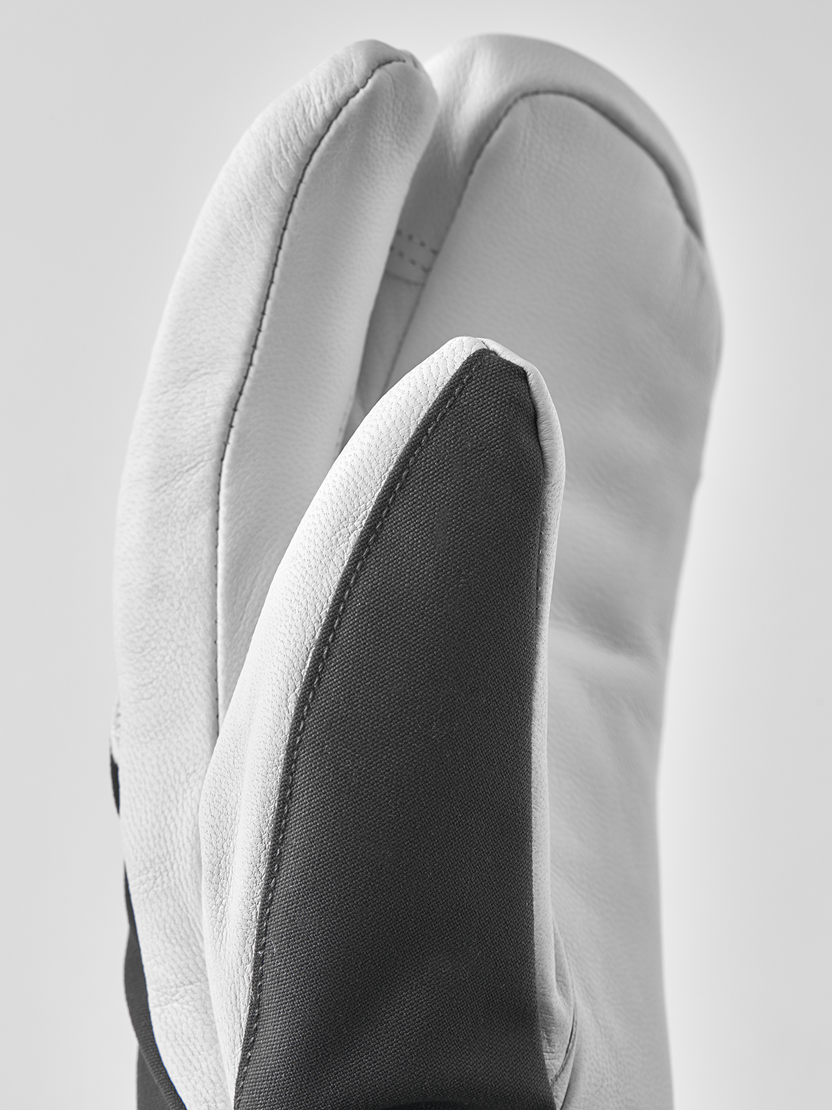 White leather ski glove with dark side panel and curved finger seam detail