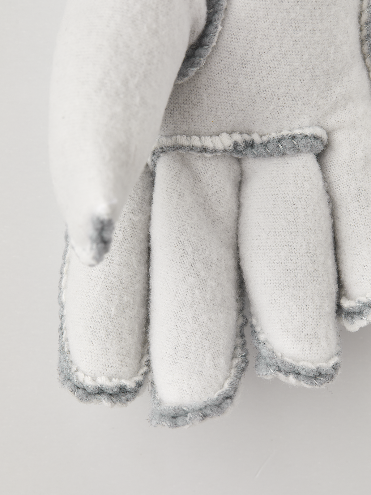 Hestra kids' off-white fleece glove liners with four-finger split and light-blue edges