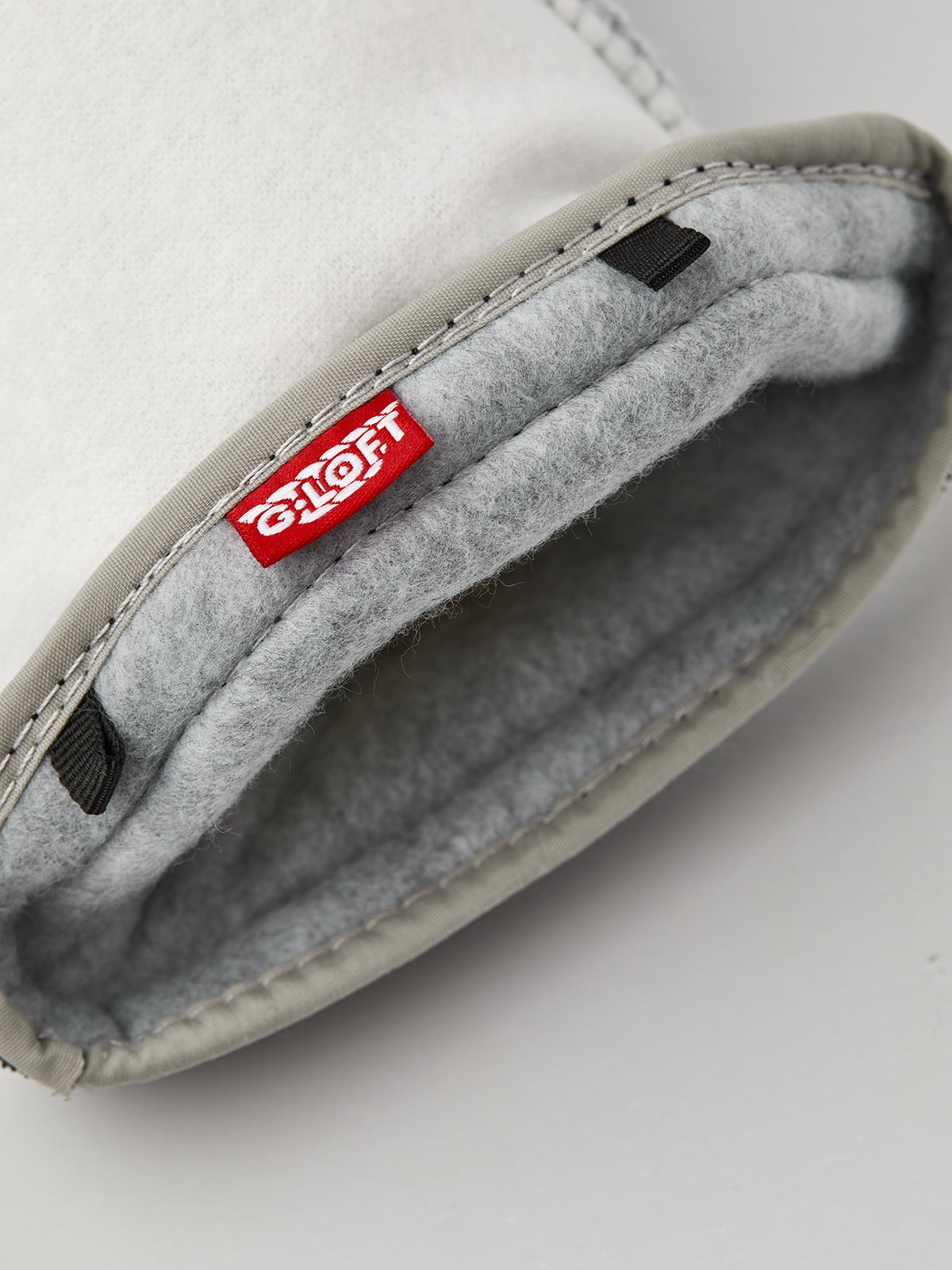 Off-white ski glove liner with gray fleece lining and stitched inner label