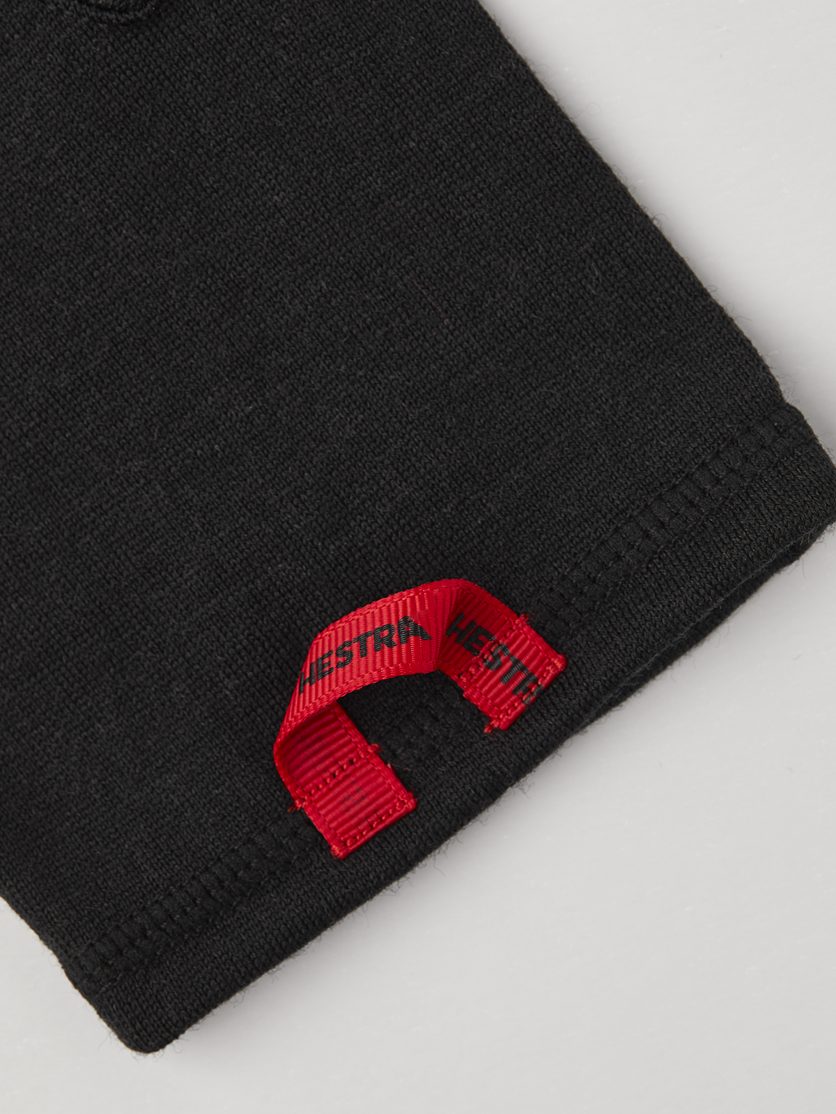 Black merino wool glove liner cuff with red brand label detail