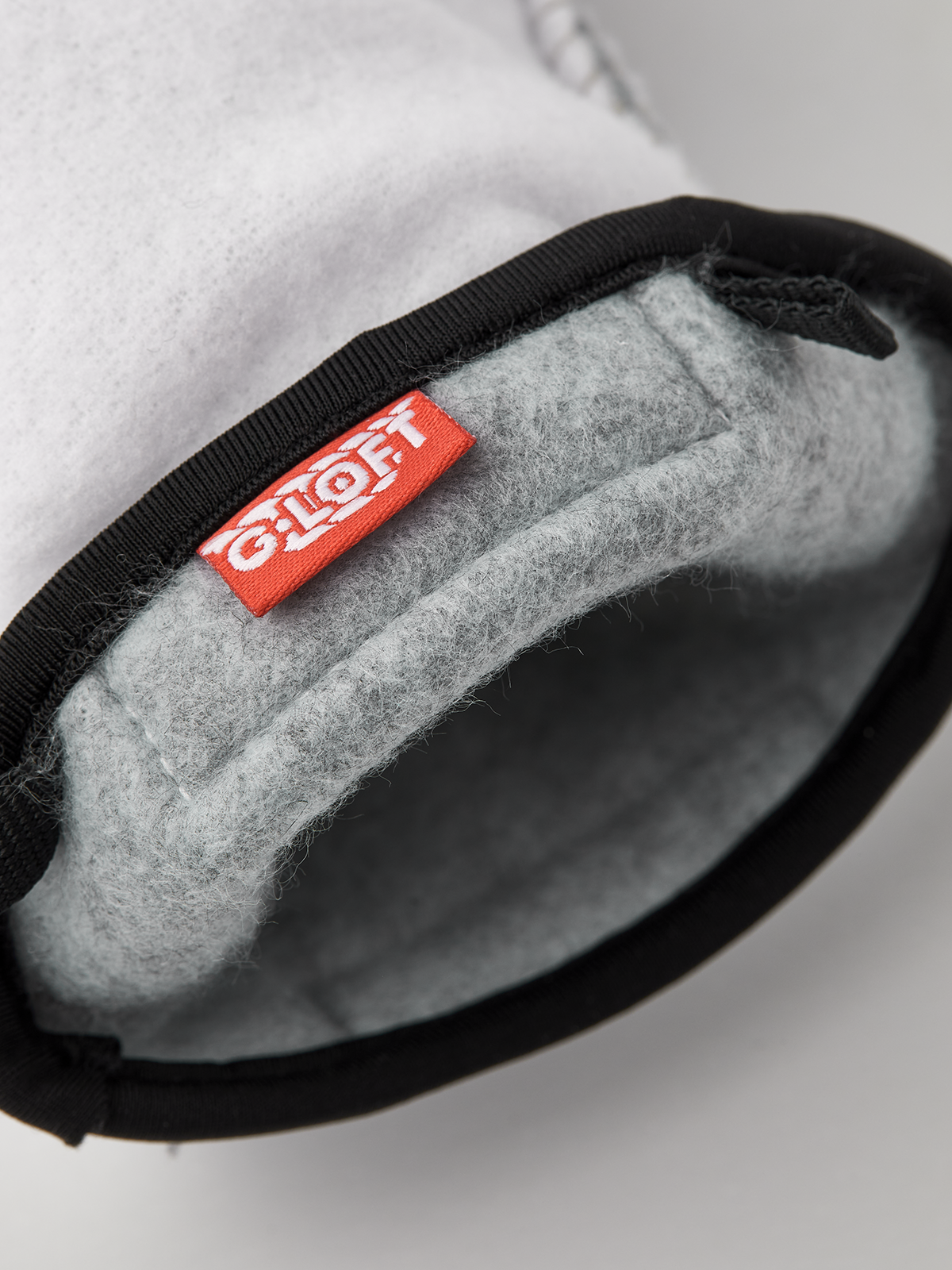 Off-white glove liners with black elastic cuff, gray felt interior and stitched seams