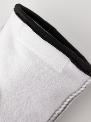 Off-white glove liner cuff with black elastic trim and white topstitching