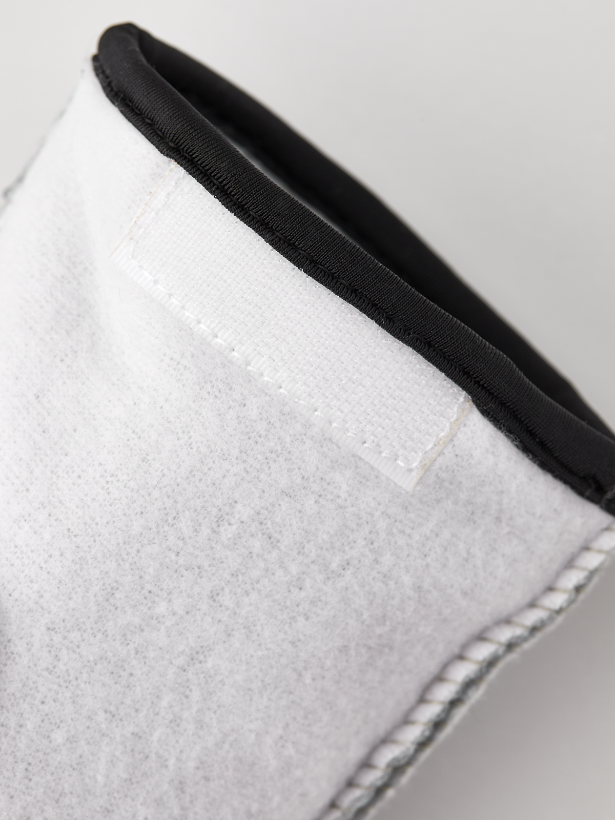 Off-white glove liner cuff with black elastic trim and white topstitching