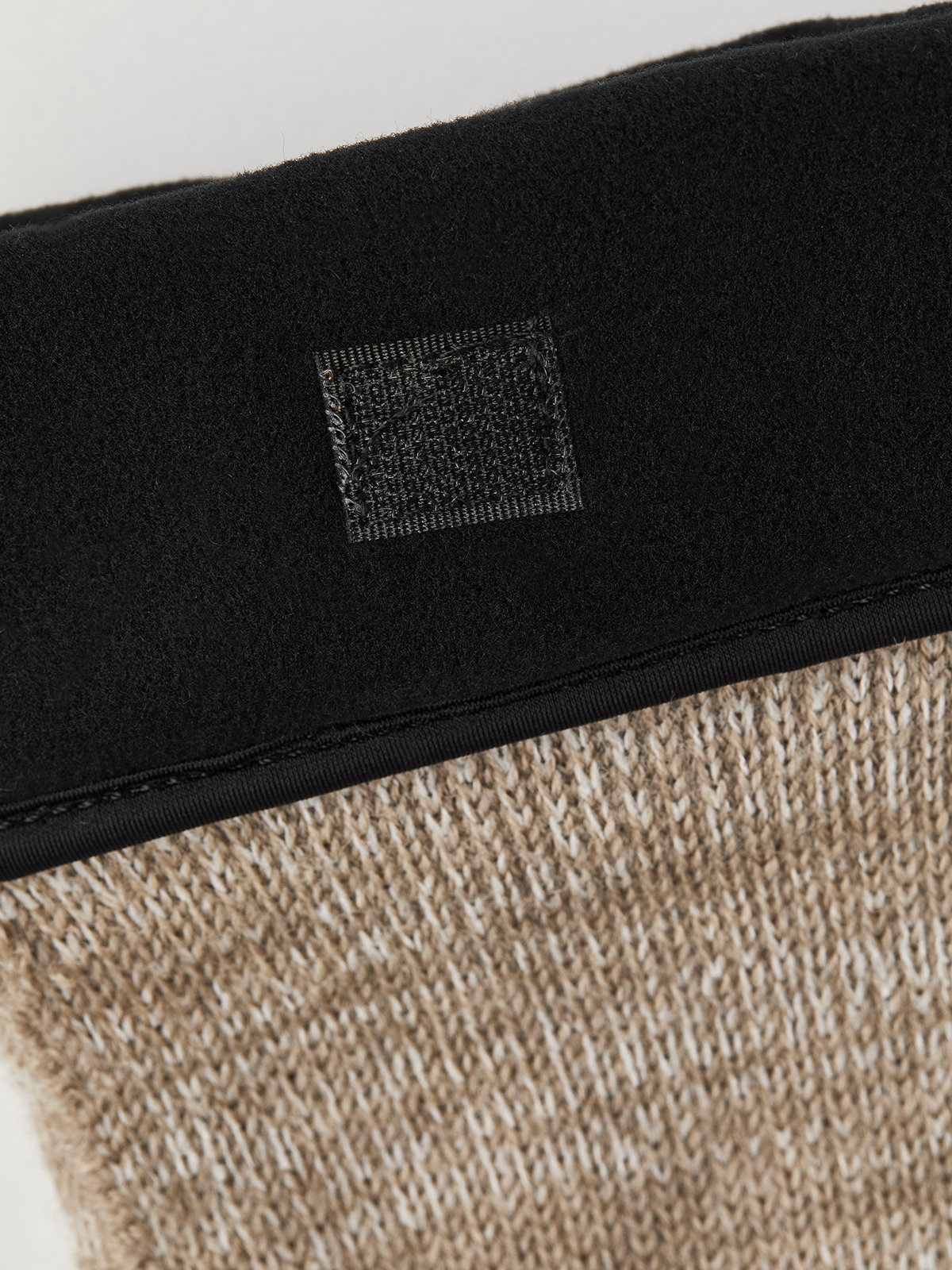 Black cuff detail on beige knit glove liner with woven logo patch