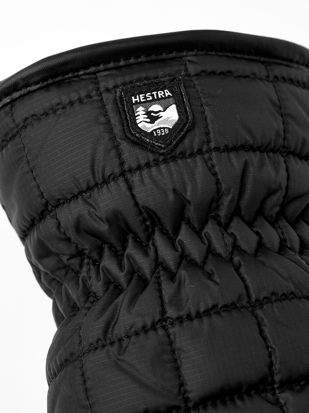Black mitten with Hestra logo patch and quilted padding on palm