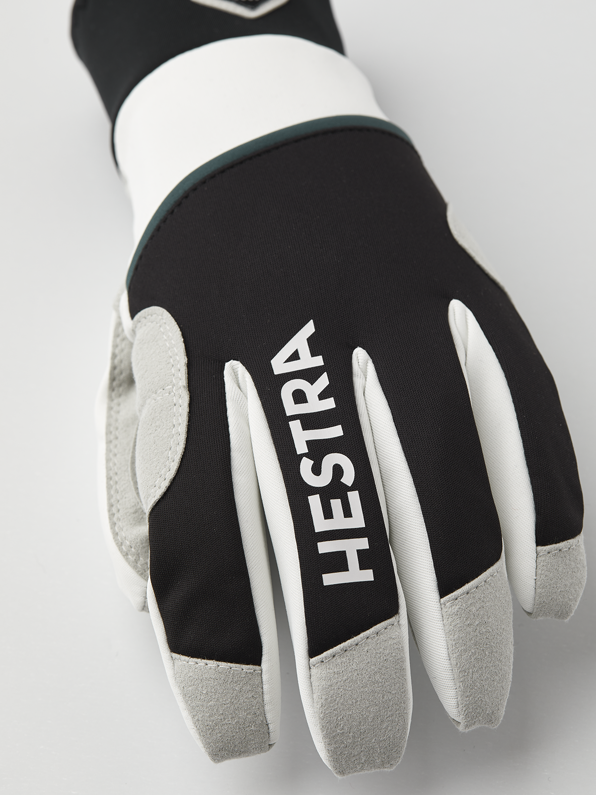 Black and off-white gloves with Hestra logo on finger panels and gray fingertips