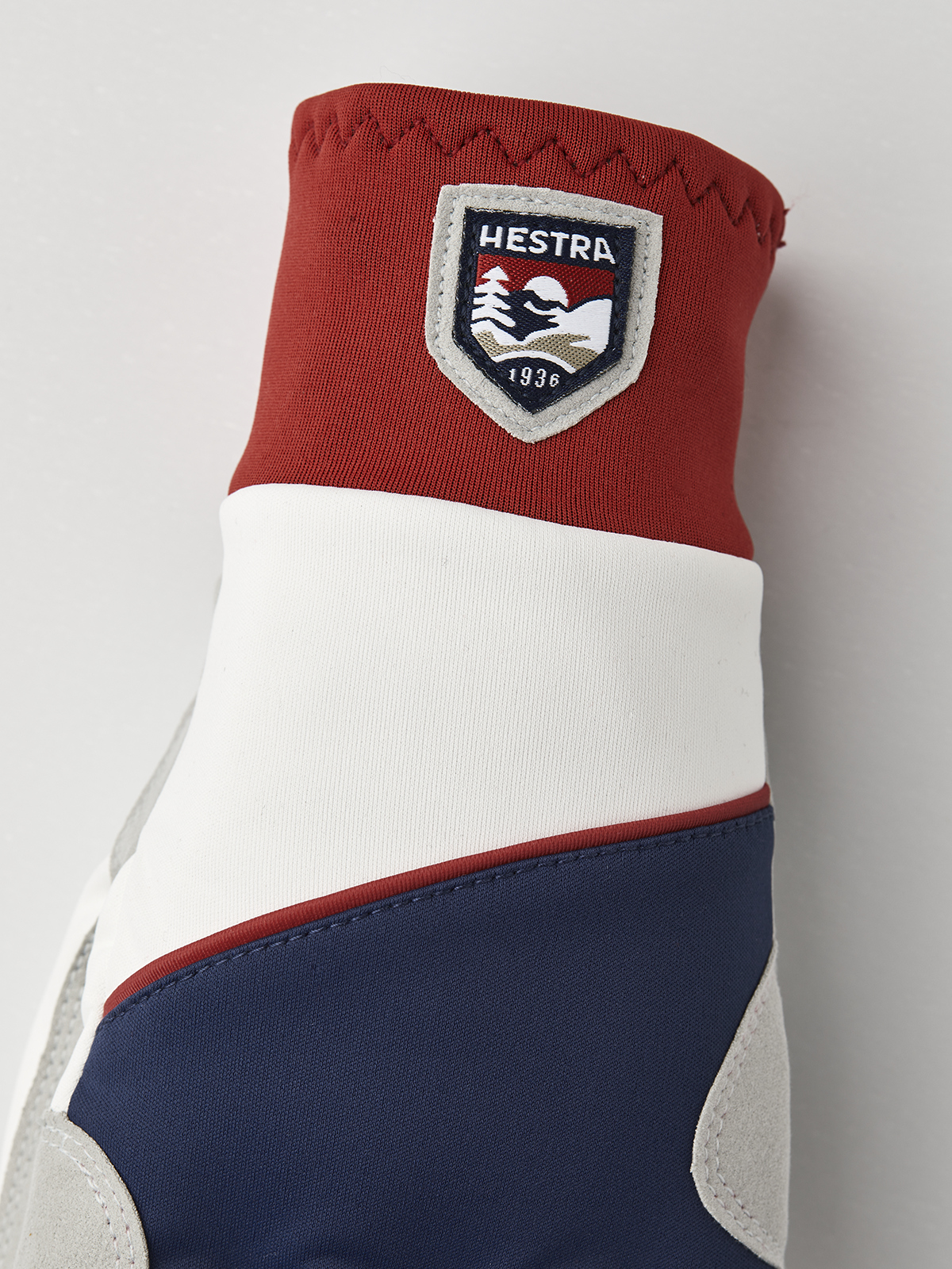 Red, off-white, and navy winter gloves with Hestra shield patch on the cuff