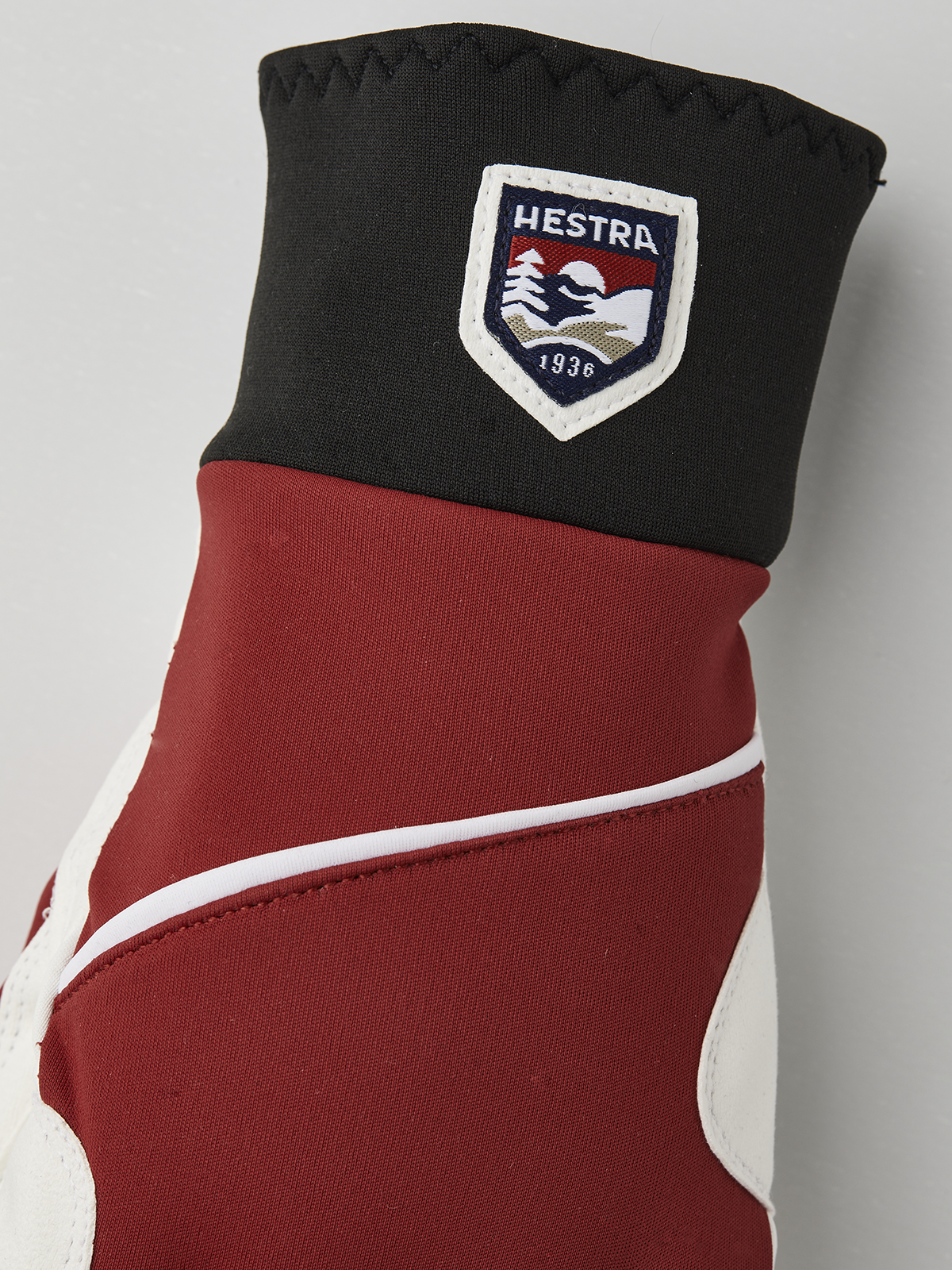Red and off-white winter gloves with black cuff panel and Hestra shield patch