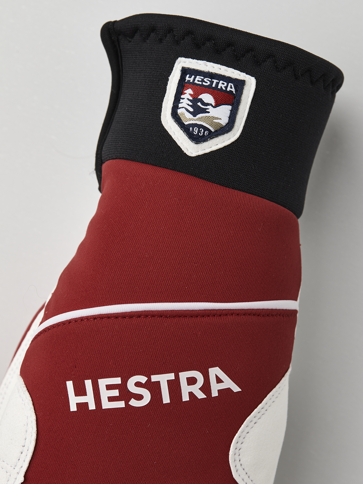 Hestra comfort tracker mittens in black, red, and off-white with logo patch