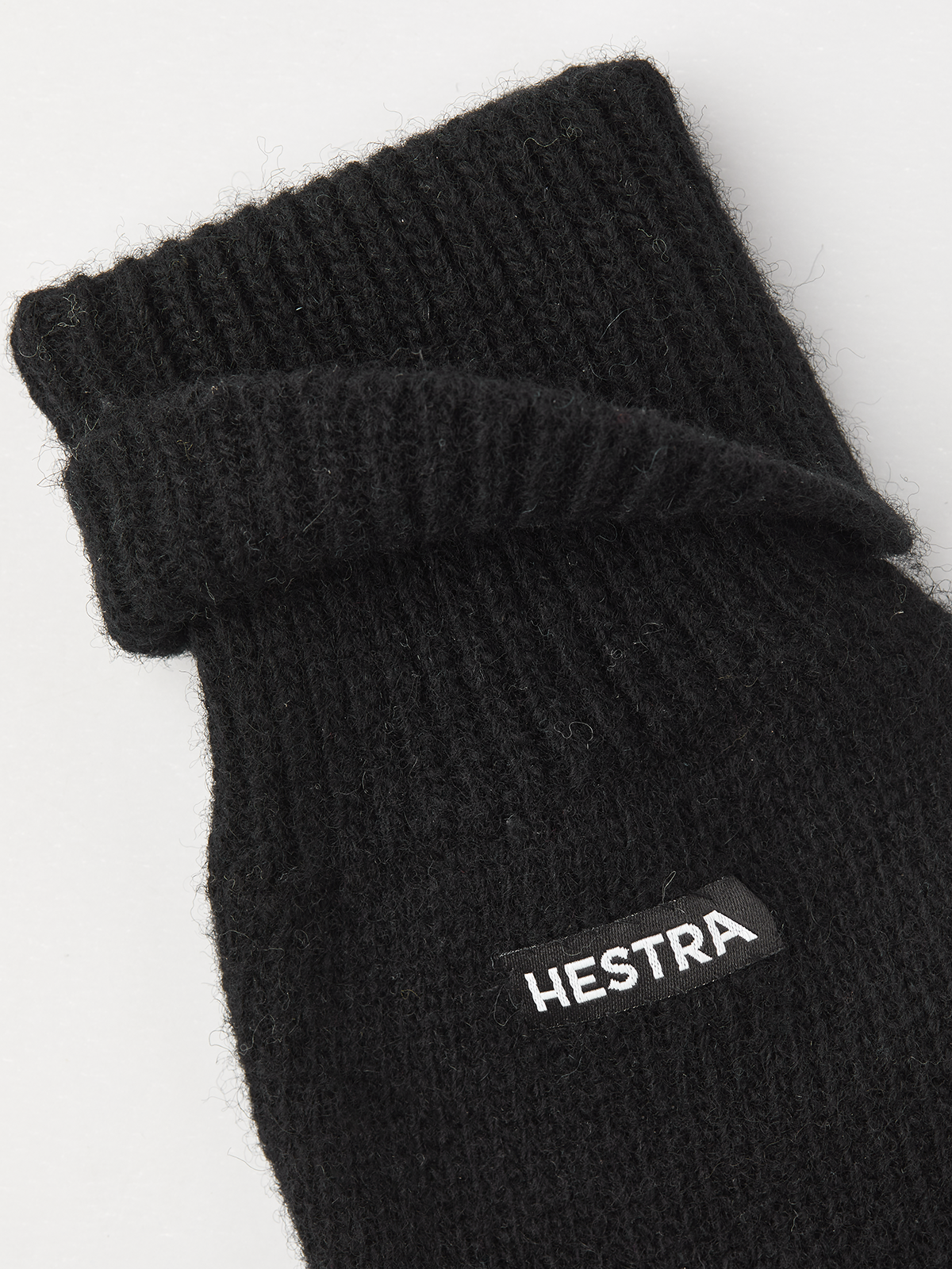 Black knit glove liner with Hestra logo patch and ribbed cuff