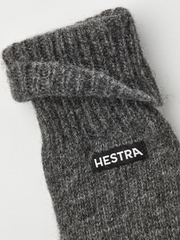 Grey knit glove liner close-up with Hestra logo patch on cuff