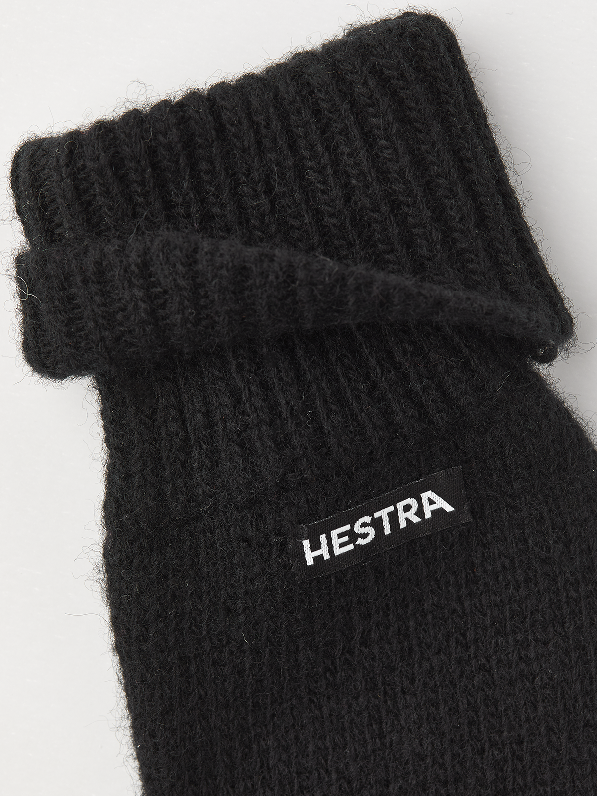Black knit mitten liner with ribbed cuff and HESTRA logo patch.