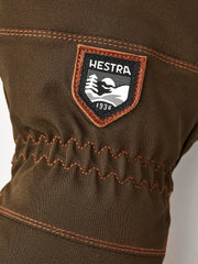 Hestra patch on dark olive glove with orange stitching and zigzag reinforced seam.