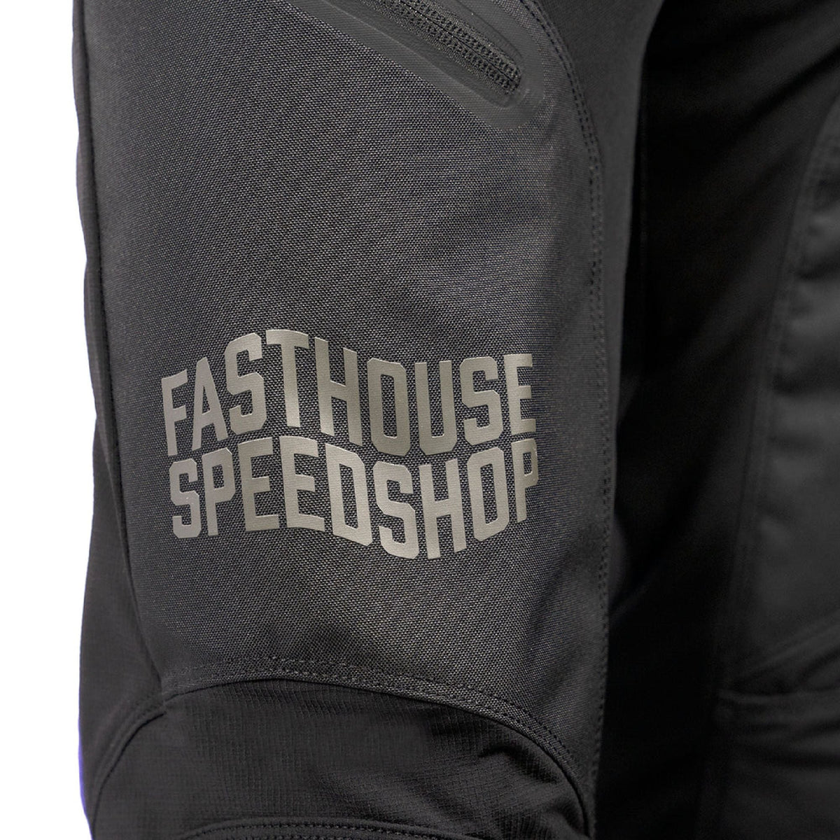 Close-up of black riding pants leg with “EASTHOUSE SPEEDSHOP” text patch