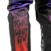 Close-up of black riding pants with purple cuff and red graphic side panel
