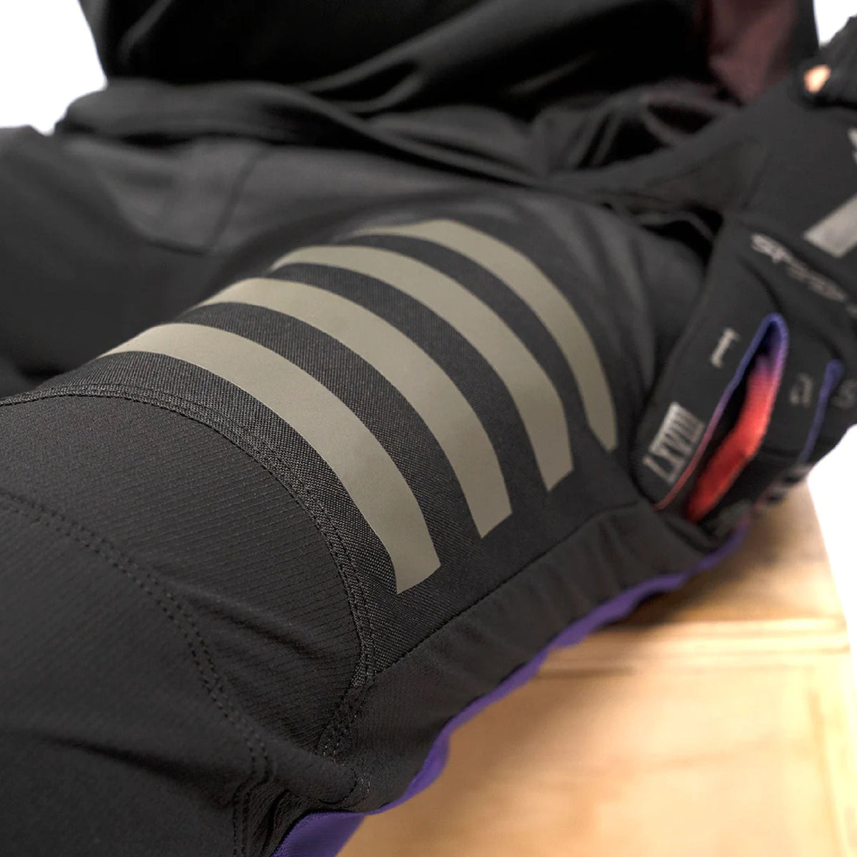 Close-up of black riding pants knee with gray reflective stripe graphic