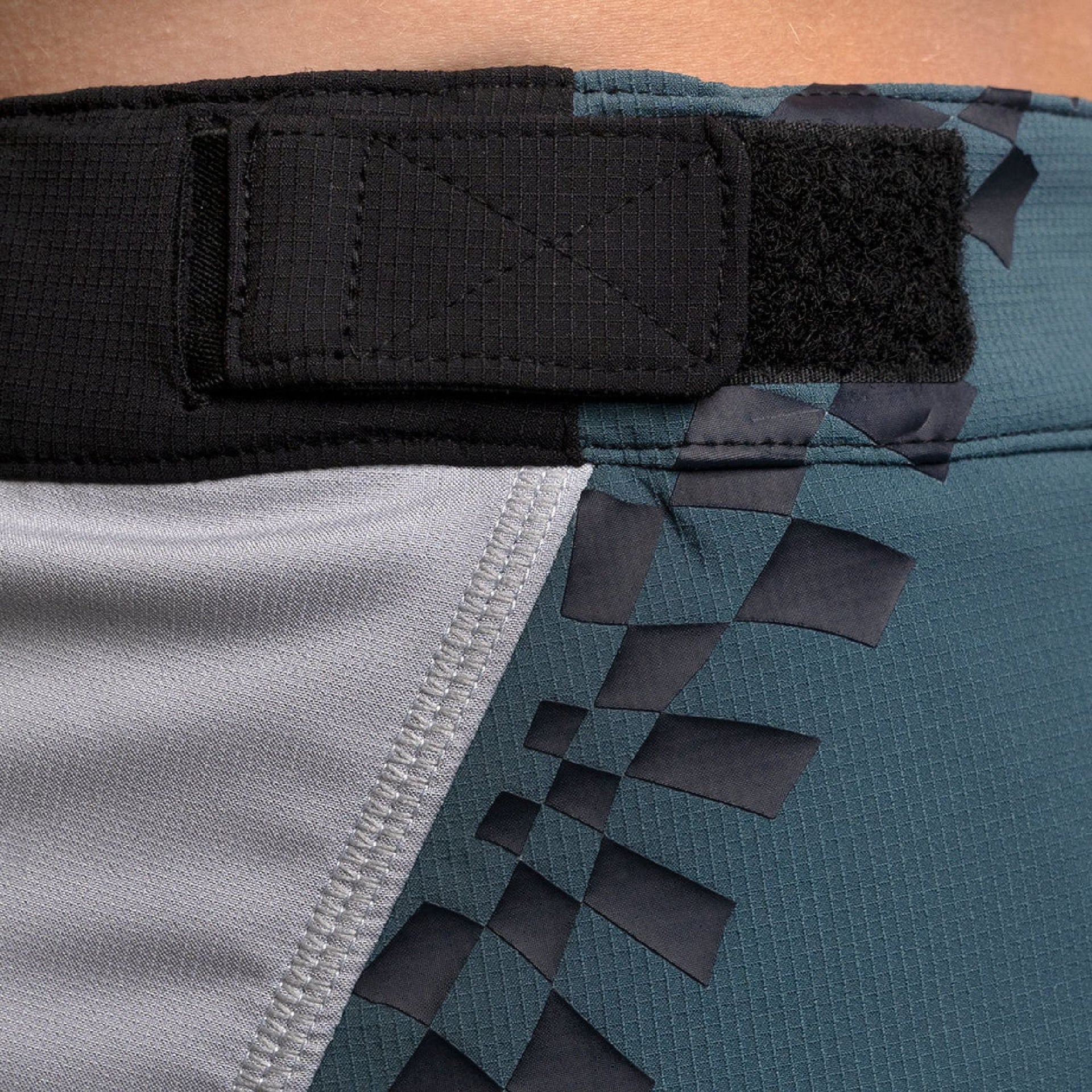 Youth shorts side view with black graphic lettering on teal panel