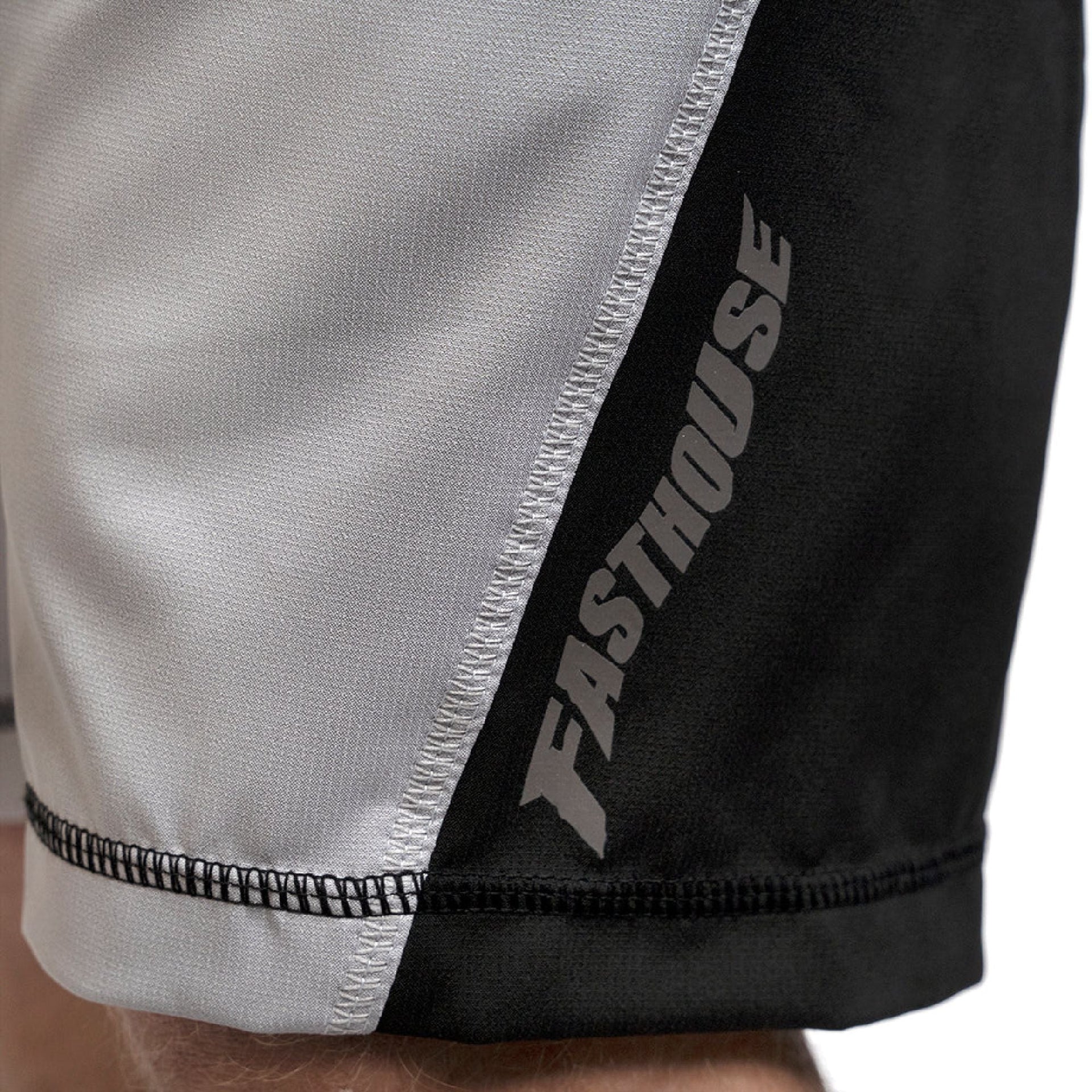 Fasthouse velocity shorts close-up: light fabric with black side panel and Fasthouse print
