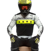 Rider wearing black cycling jersey with white sleeves and neon yellow star band.