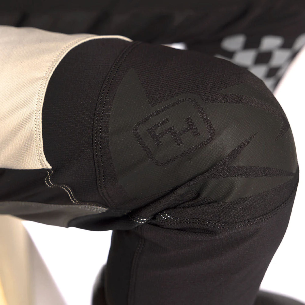 Cream and black riding pants with logo patch and stitched knee panel detail