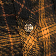 Round brand patch on orange-and-black plaid flannel fabric