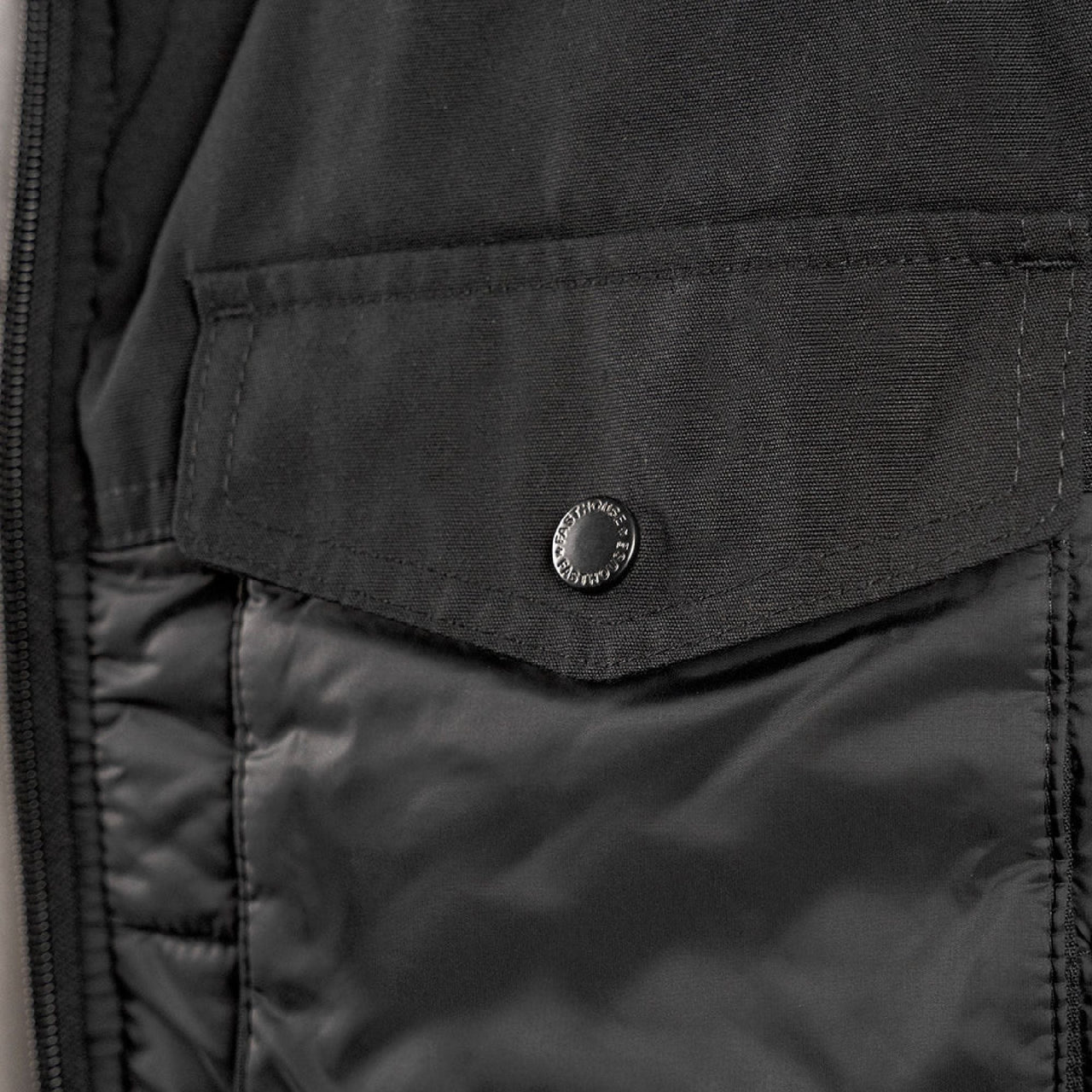 Black puffer vest with snap-flap chest pocket and quilted front panel