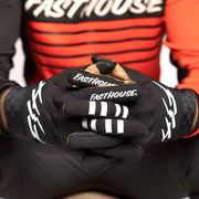 Black motocross glove with white Fasthouse branding on knuckles and fingers
