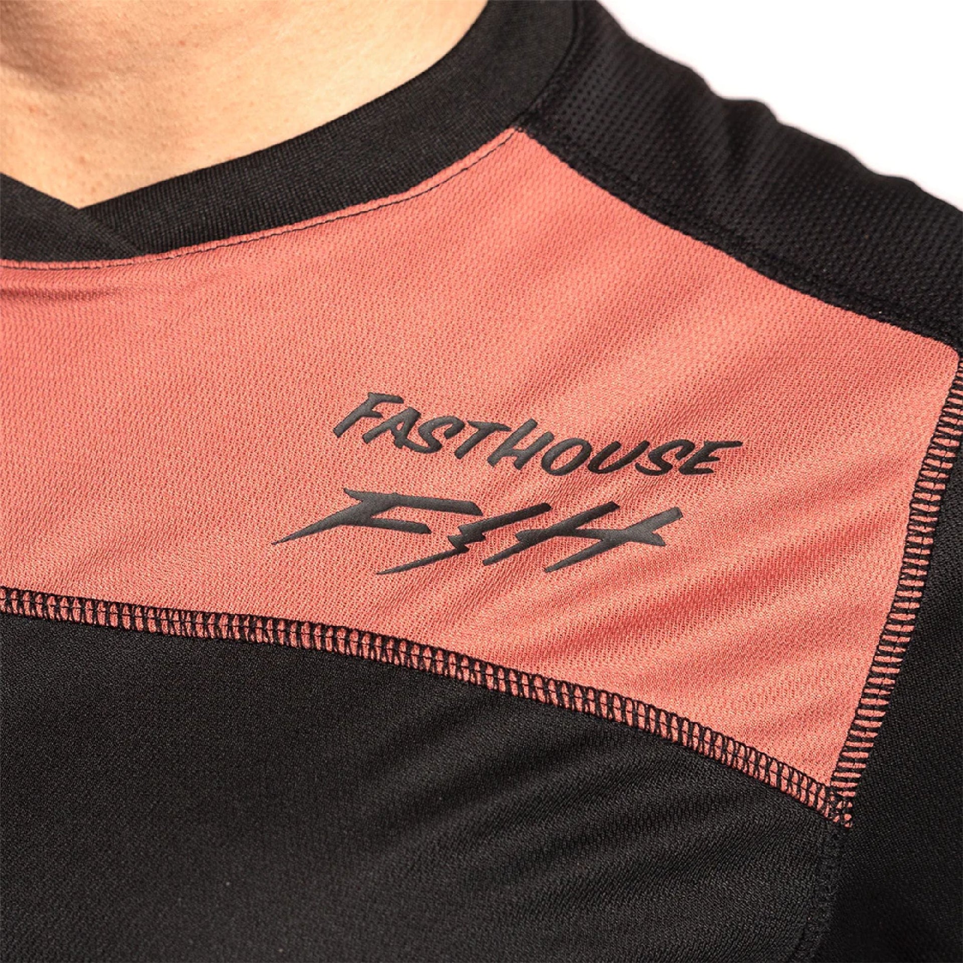 Women's riding jersey close-up, FastHouse logo on orange-mauve chest panel
