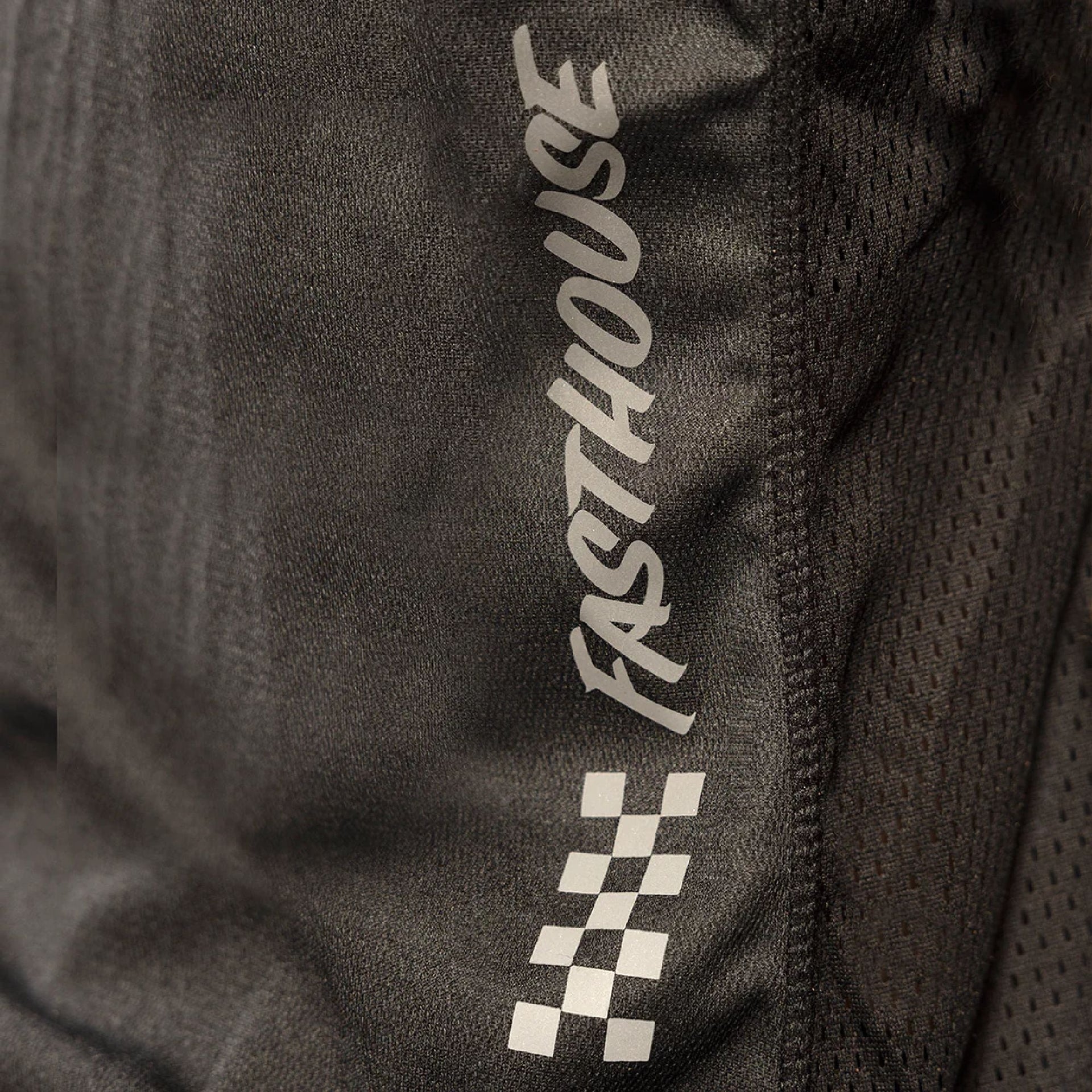 Close-up of charcoal/black jersey fabric with Fasthouse vertical logo and check print
