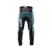 Youth motocross pants in teal with black sections, checkered waistband, Fasthouse logo.